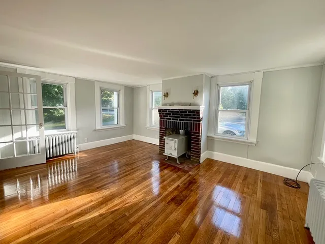 a view of empty room with wooden floor and fireplace