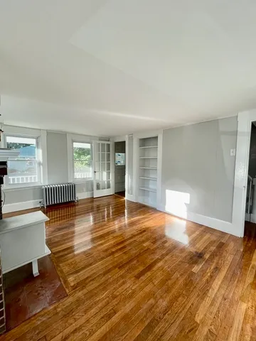a view of empty room with wooden floor and floor to ceiling window