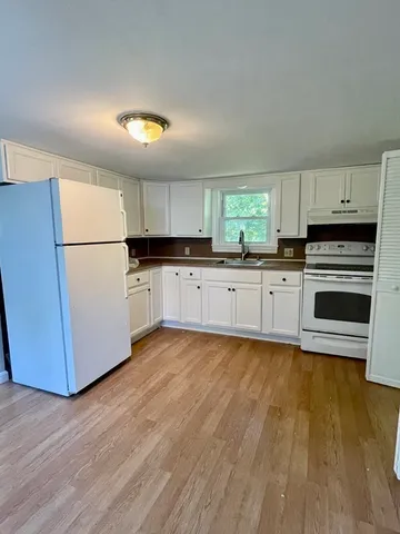 a kitchen with granite countertop a refrigerator and a stove top oven