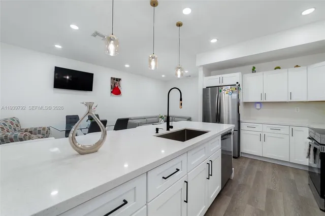 a kitchen with stainless steel appliances granite countertop a sink and a refrigerator