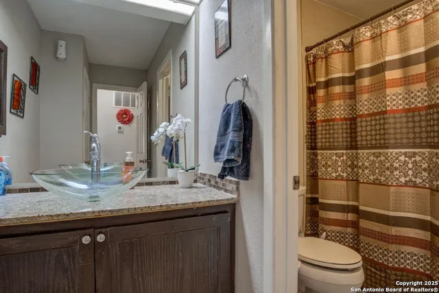 a bathroom with a granite countertop sink toilet and shower