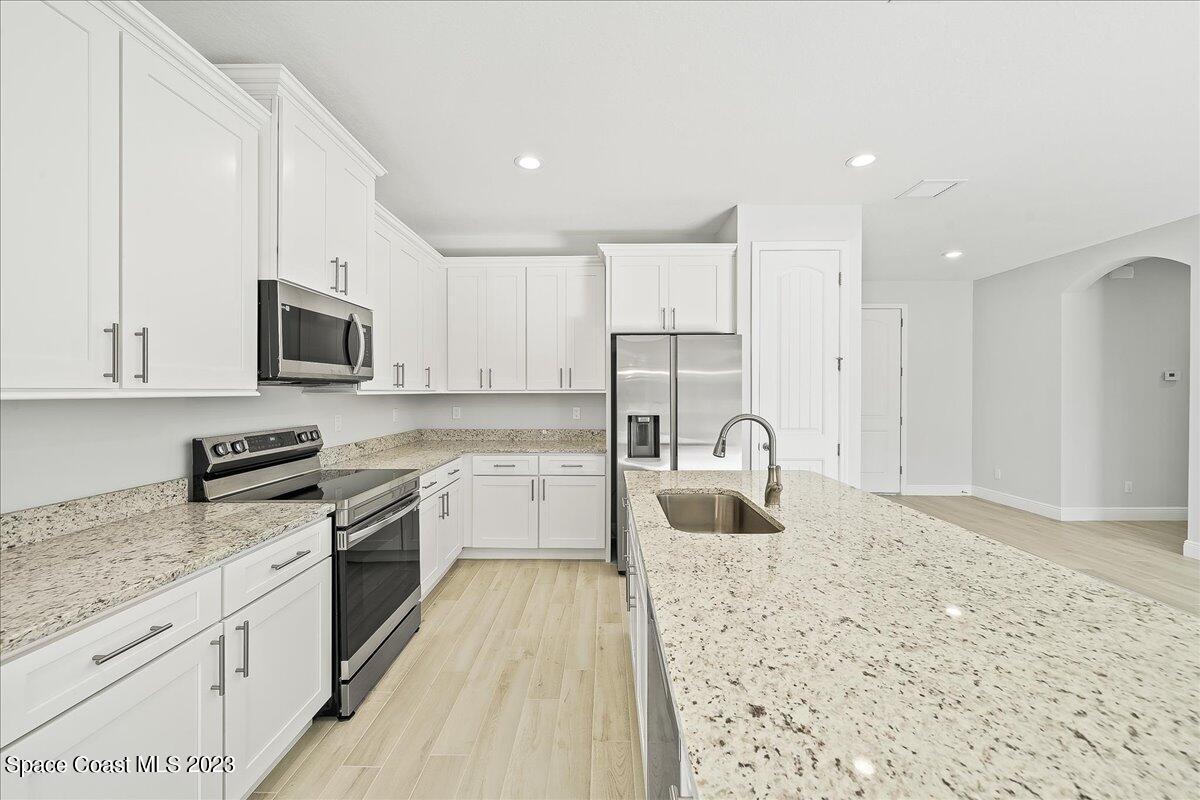 560 Topeka Road Southwest Palm Bay, FL 32908 - Photo 3 of 26 a kitchen with granite countertop a stove sink and microwave