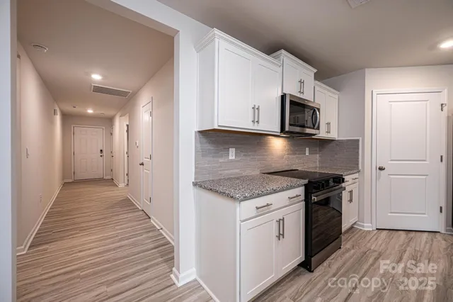 a kitchen with stainless steel appliances a table chairs refrigerator microwave and cabinets