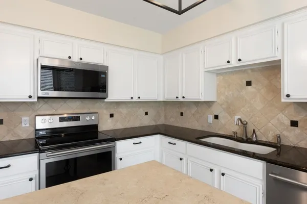 a kitchen with granite countertop white cabinets and stainless steel appliances