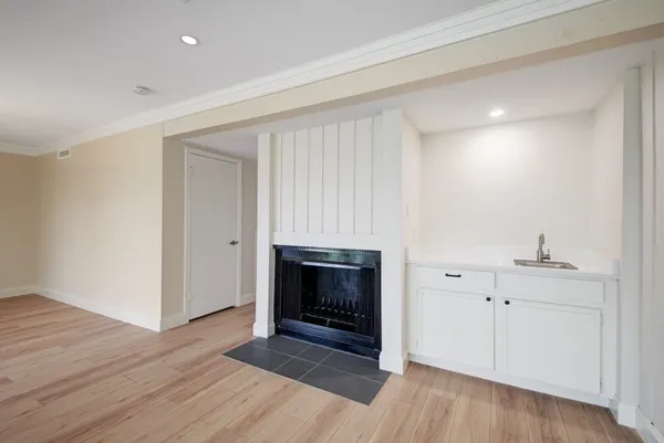 a view of an empty room with wooden floor and a fireplace
