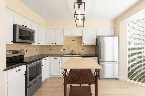 a kitchen with a refrigerator a microwave a stove and white cabinets