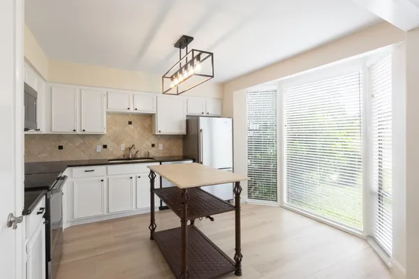 a kitchen with kitchen island a table chairs refrigerator and microwave
