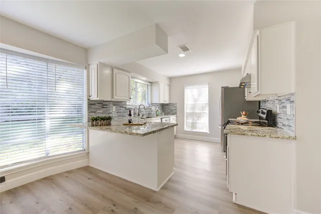 a kitchen with stainless steel appliances granite countertop a stove a sink dishwasher and a refrigerator