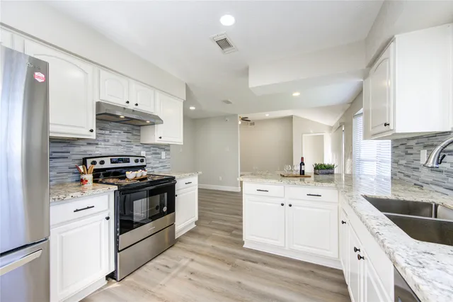 a kitchen with stainless steel appliances granite countertop a sink stove and refrigerator