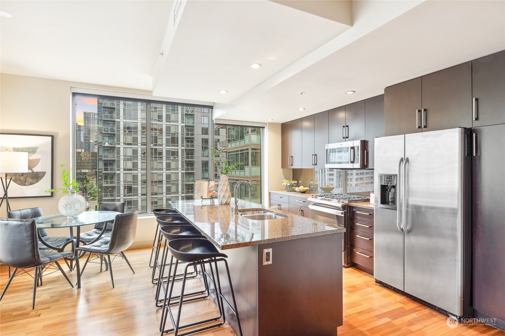 910 Lenora Street, Unit S907 Seattle, WA 98121 - Photo 21 of 38 a kitchen with stainless steel appliances granite countertop a refrigerator a stove a dining table and chairs with wooden floor