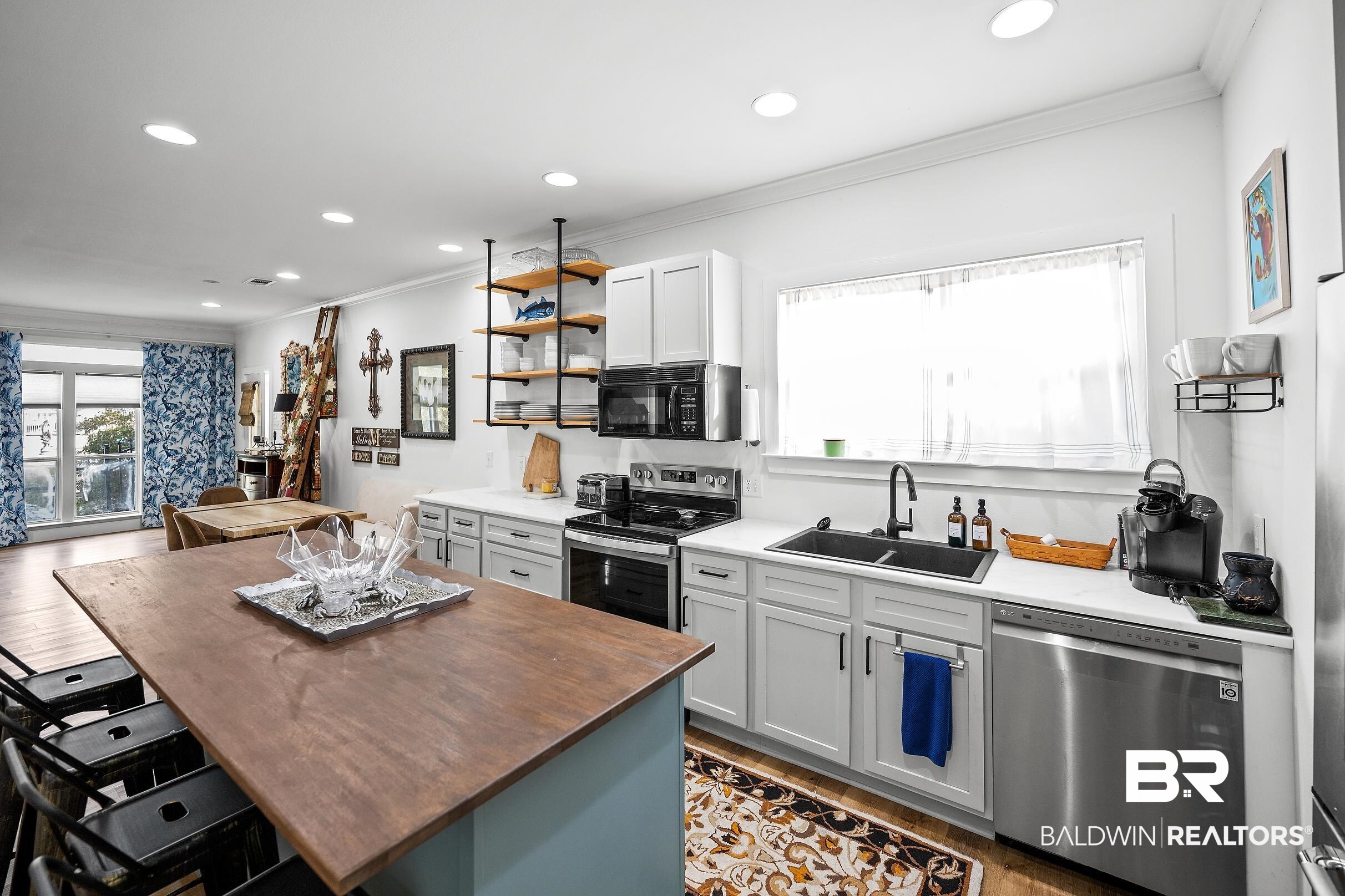 8490 Bay View Drive Foley, AL 36535 - Photo 51 of 67 Kitchen featuring ornamental molding, open shelves, appliances with stainless steel finishes, butcher block counters, and a kitchen breakfast bar