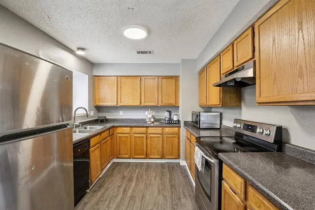 a kitchen with stainless steel appliances granite countertop sink stove refrigerator and cabinets