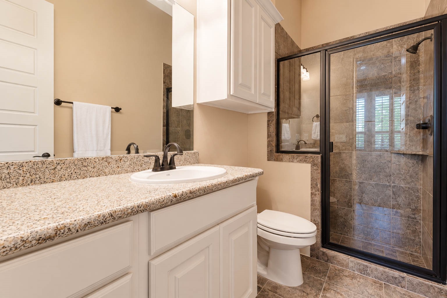 91 Lake View Loop Fulshear, TX 77441 - Photo 32 of 42 This guest bathroom mirrors the style of the other, featuring a spacious vanity with white cabinetry, granite countertops, and a walk in shower with a neutral tile surround.