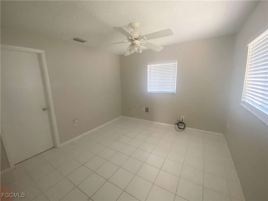 2258 Iris Way Fort Myers, FL 33905 - Photo 5 of 9 an empty room with a window and a fan