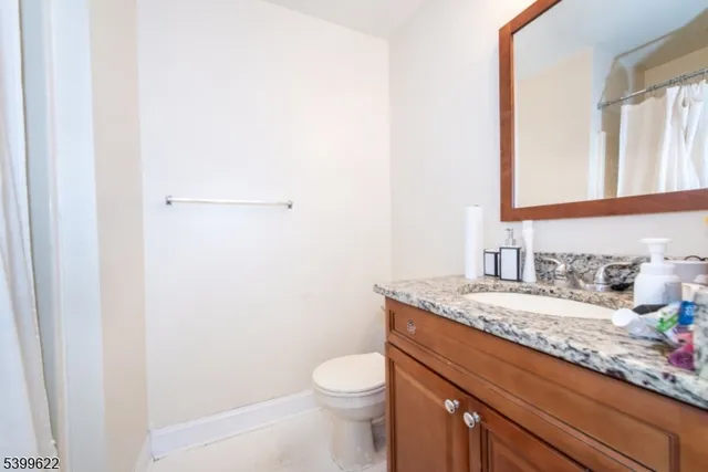 a bathroom with a granite countertop toilet sink and mirror
