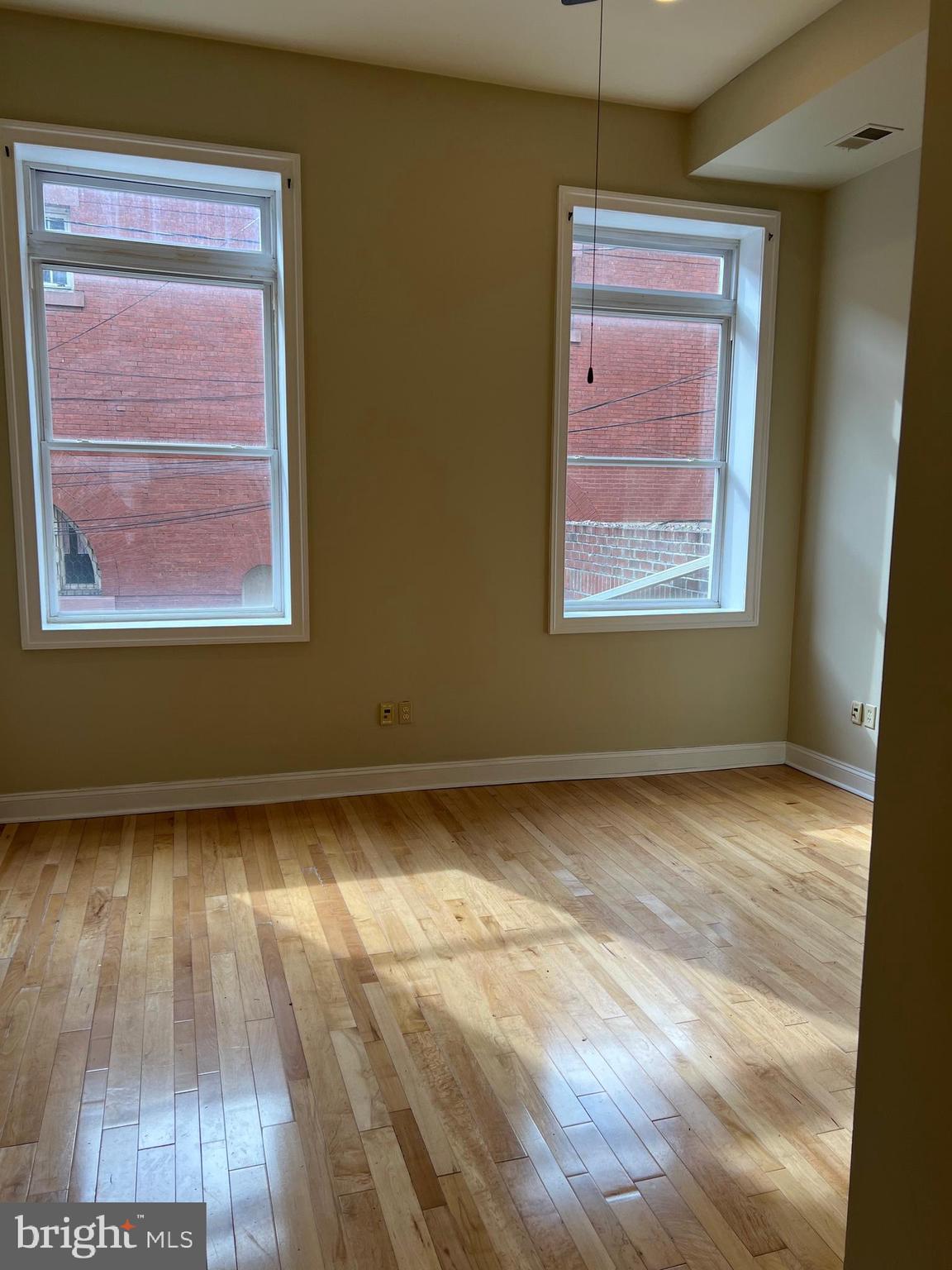 1230 North Calvert Street, Unit 1 Baltimore, MD 21202 - Photo 11 of 14 a view of an empty room with wooden floor and a window