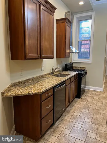 a kitchen with a sink a stove cabinets and a wooden floor