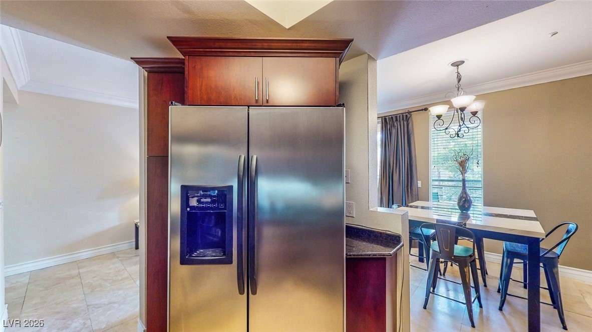 260 East Flamingo Road, Unit 229 Las Vegas, NV 89169 - Photo 35 of 41 Kitchen with stainless steel fridge, crown molding, hanging lights, bold wood finish cabinetry, and light tile patterned floors