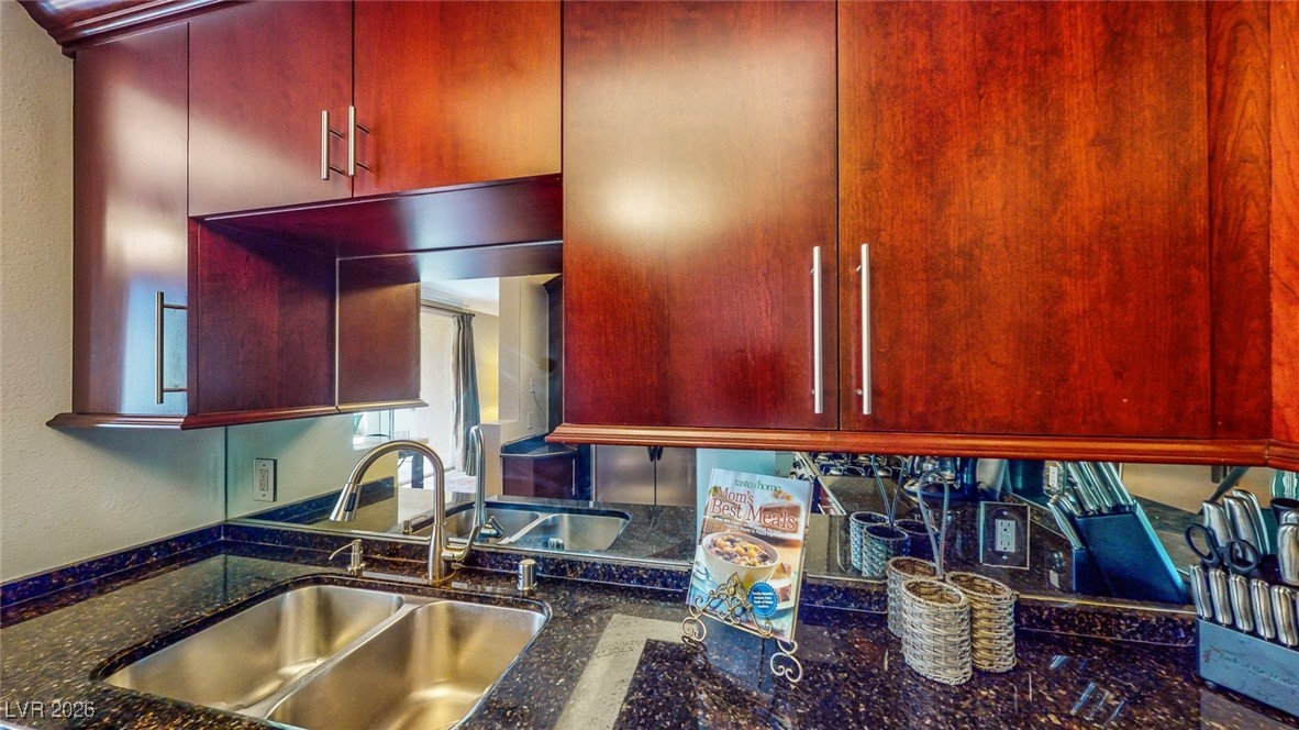 260 East Flamingo Road, Unit 229 Las Vegas, NV 89169 - Photo 36 of 41 Kitchen featuring dark stone counters, bold wood finish cabinets, and a textured wall