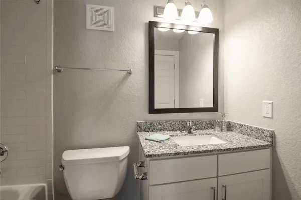 a bathroom with a granite countertop sink toilet and mirror