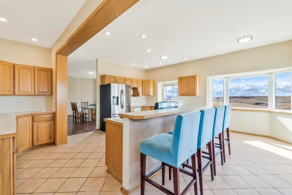 a dining hall with stainless steel appliances kitchen island granite countertop a table and chairs in it