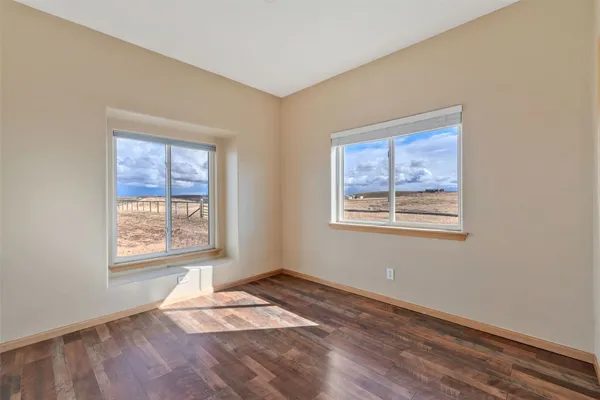 a view of an empty room with a window and wooden floor