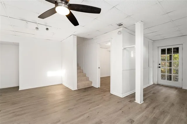 an empty room with wooden floor ceiling fan