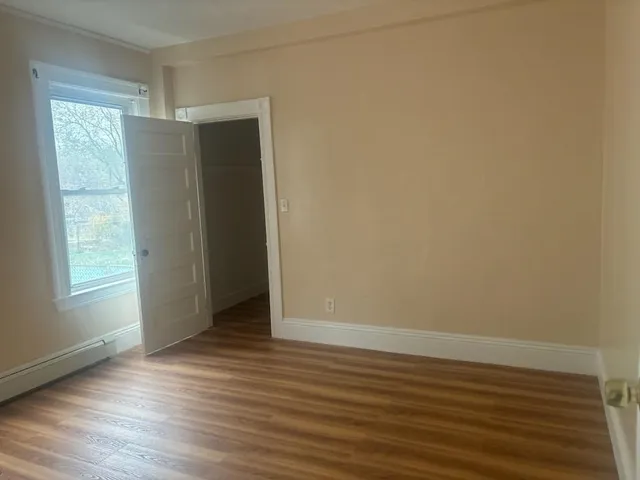a view of an empty room with wooden floor and a window