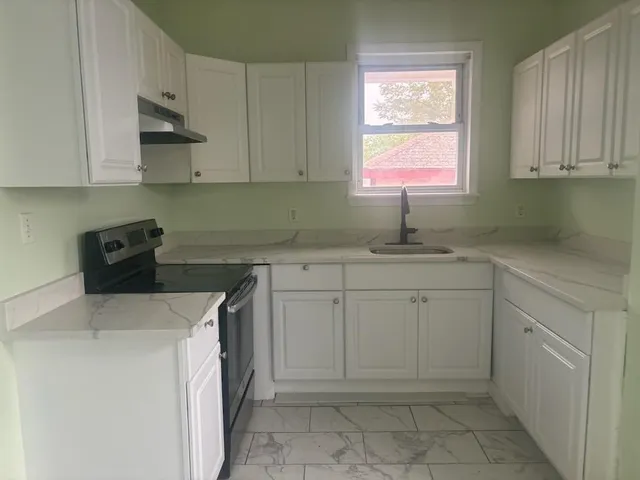 a kitchen with white cabinets and sink