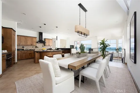 a dining room with stainless steel appliances kitchen island granite countertop a table chairs and a refrigerator