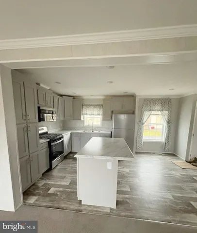 a kitchen with kitchen island a counter top space a sink stainless steel appliances and cabinets