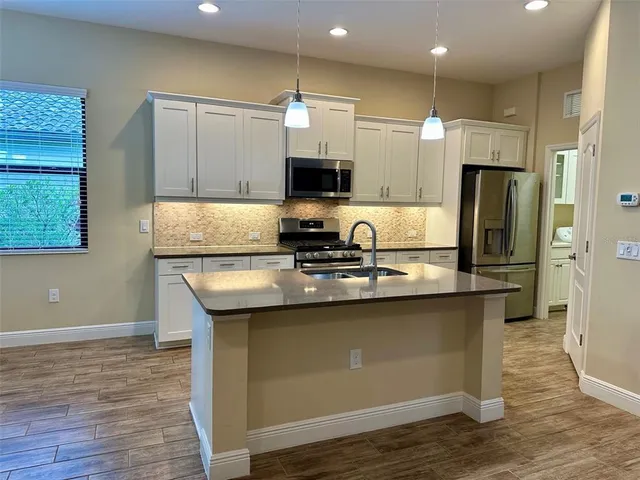a kitchen with kitchen island granite countertop a sink and refrigerator