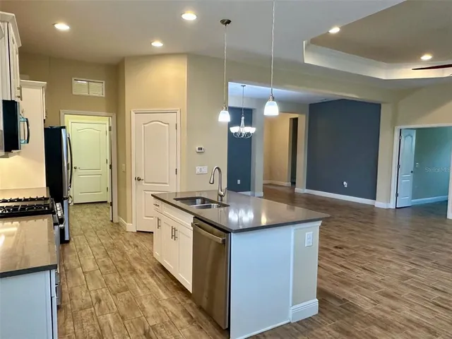 a kitchen with stainless steel appliances granite countertop a sink a stove and a wooden floors