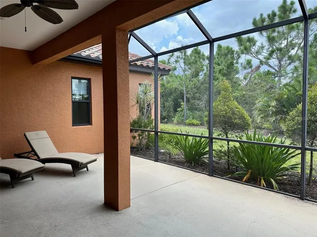 a view of a patio with chairs and floor to ceiling window and garden