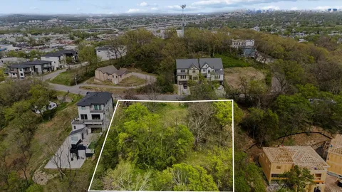 an aerial view of a residential houses with outdoor space and trees