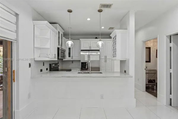 a large kitchen with stainless steel appliances kitchen island granite countertop a refrigerator and cabinets