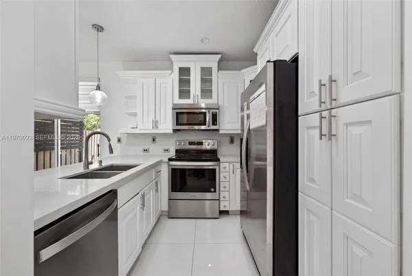 a kitchen with stainless steel appliances granite countertop a refrigerator a sink a stove and white cabinets