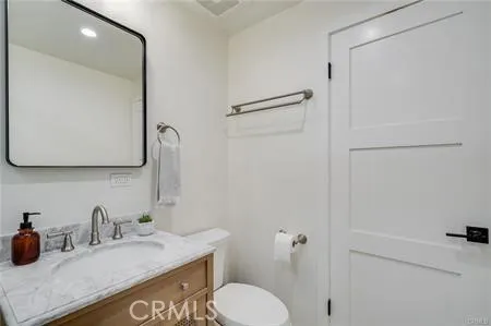 a bathroom with a granite countertop sink toilet and mirror