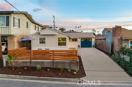 a view of a white house with a small yard and potted plants