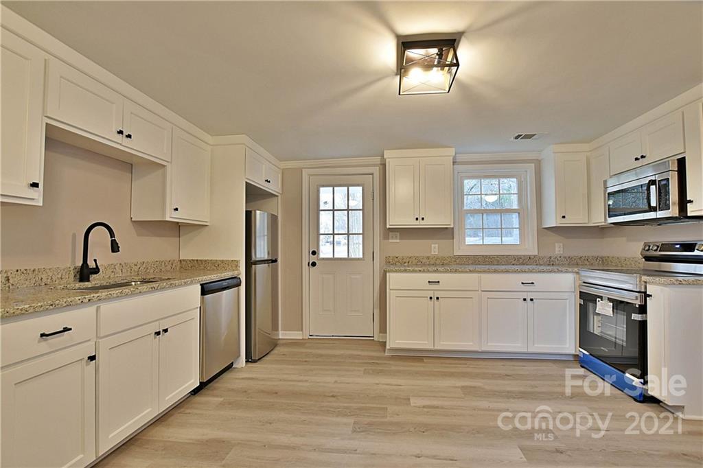 2441 State Rd S-29-305 Lancaster, SC 29720 - Photo 11 of 29 a kitchen with granite countertop white cabinets and appliances