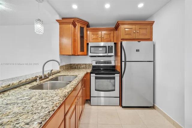 a kitchen with stainless steel appliances granite countertop a sink and a refrigerator