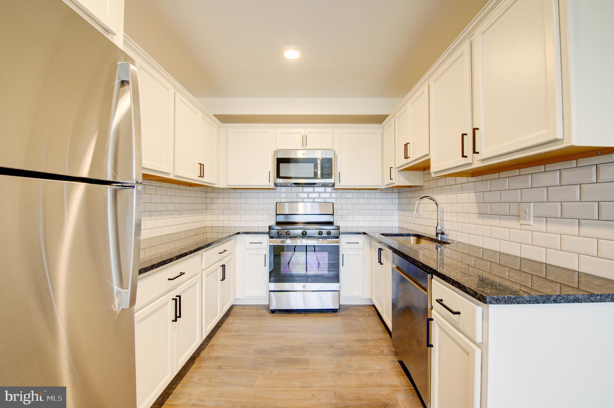 6649 Ridge Avenue, Unit B406 Philadelphia, PA 19128 - Photo 1 of 8 a kitchen with granite countertop white cabinets and white appliances