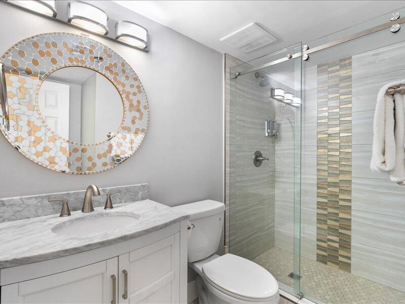 1044 Highway 98, Unit 101 Destin, FL 32541 - Photo 19 of 29 a bathroom with a granite countertop toilet a sink and shower