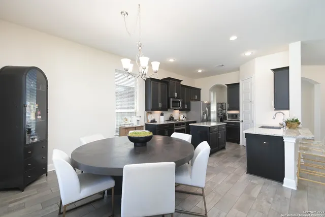 a dining room with furniture a chandelier and kitchen view