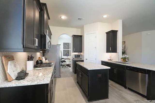 a kitchen with stainless steel appliances granite countertop a sink a stove and a refrigerator