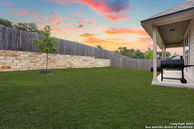 a view of a backyard with a garden and wooden fence
