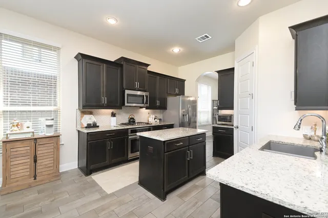 a kitchen with kitchen island granite countertop stainless steel appliances and wooden cabinets