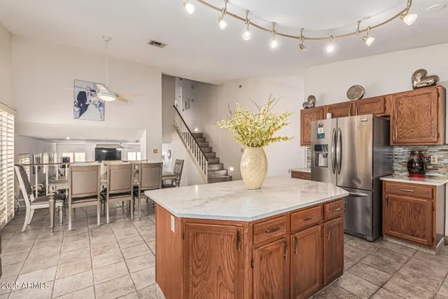 a kitchen with stainless steel appliances kitchen island granite countertop a table chairs and a refrigerator