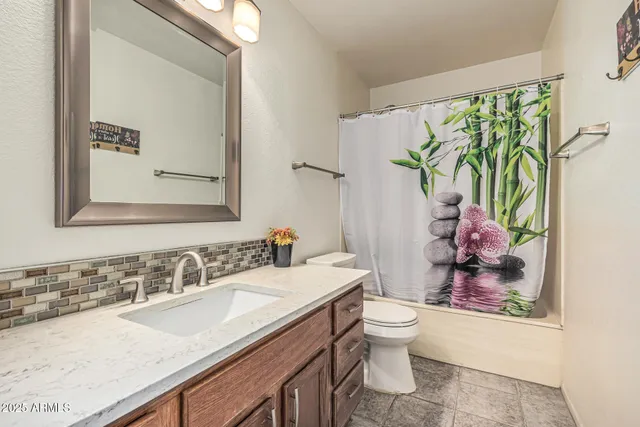 a bathroom with a granite countertop sink a toilet and a mirror
