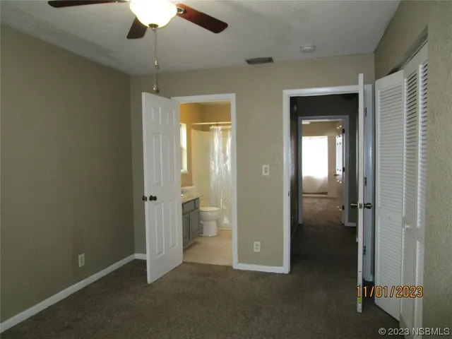 an empty room with closet and a chandelier fan
